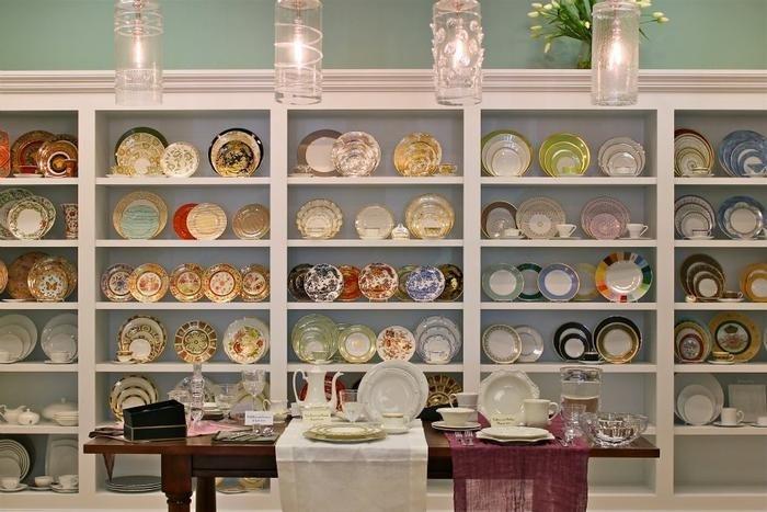 A wall of plates and a table with table setting items inside The Globe shop.